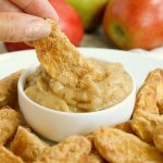 hand dipping air fried apple wedge in caramel