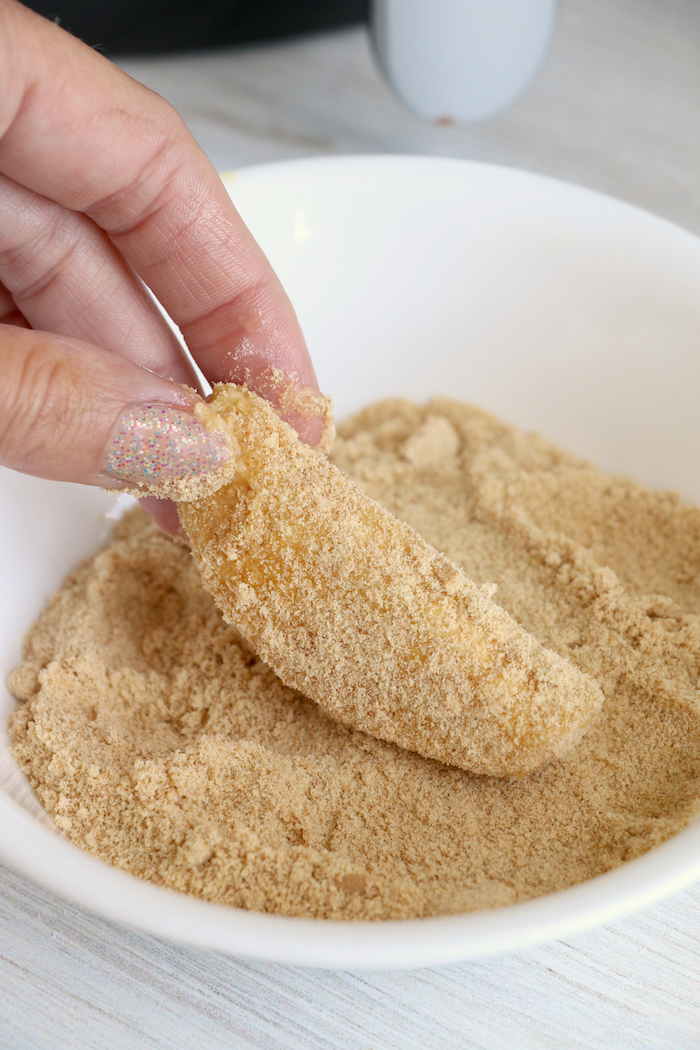 Dredging apple slices in graham cracker mixture