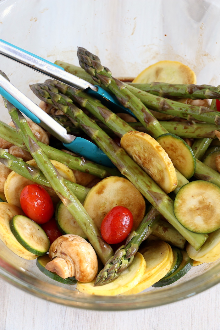 Mixing in marinade with an assortment of vegetables