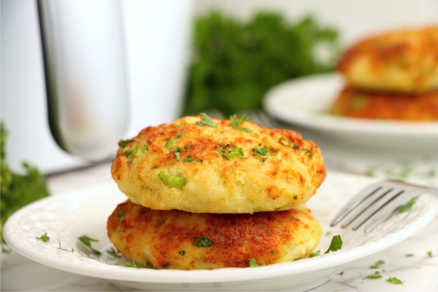 stack of crab cakes on a plate in front of an air fryer