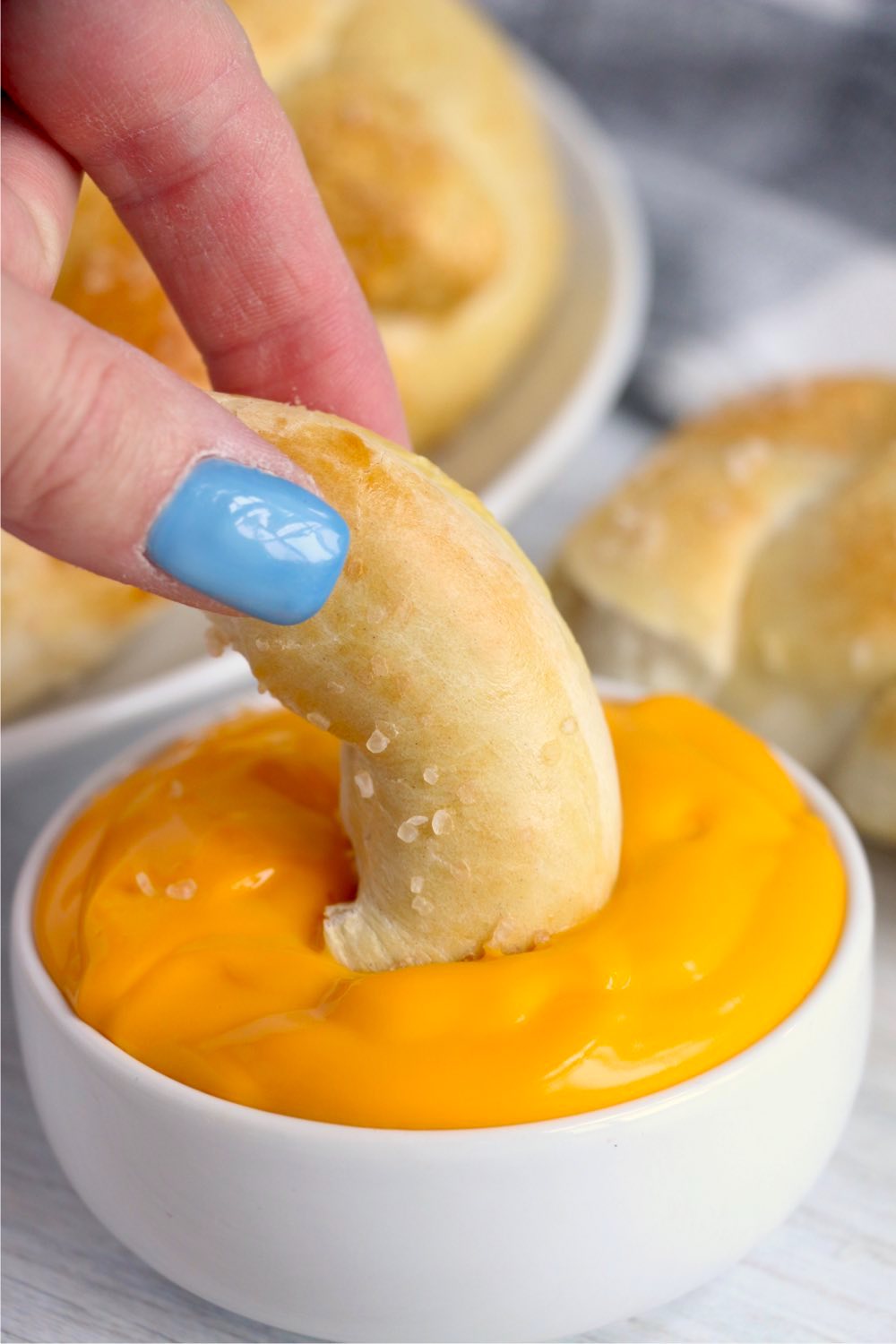 dipping a piece of pretzel into cheese dip
