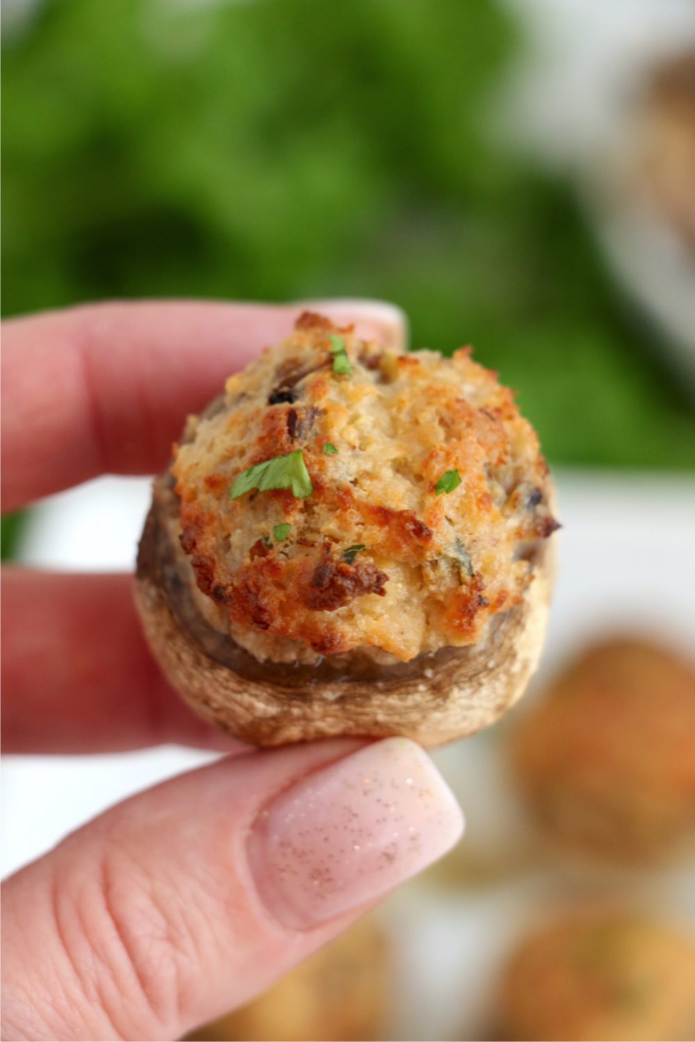 fingers holding stuffed mushroom cap