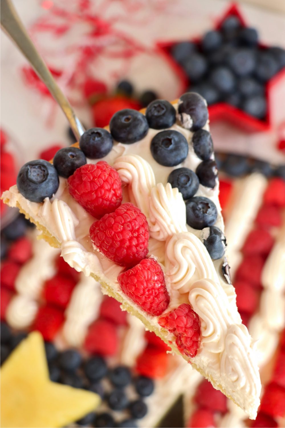 serving spatula holding a slice of red white and blue fruit pizza