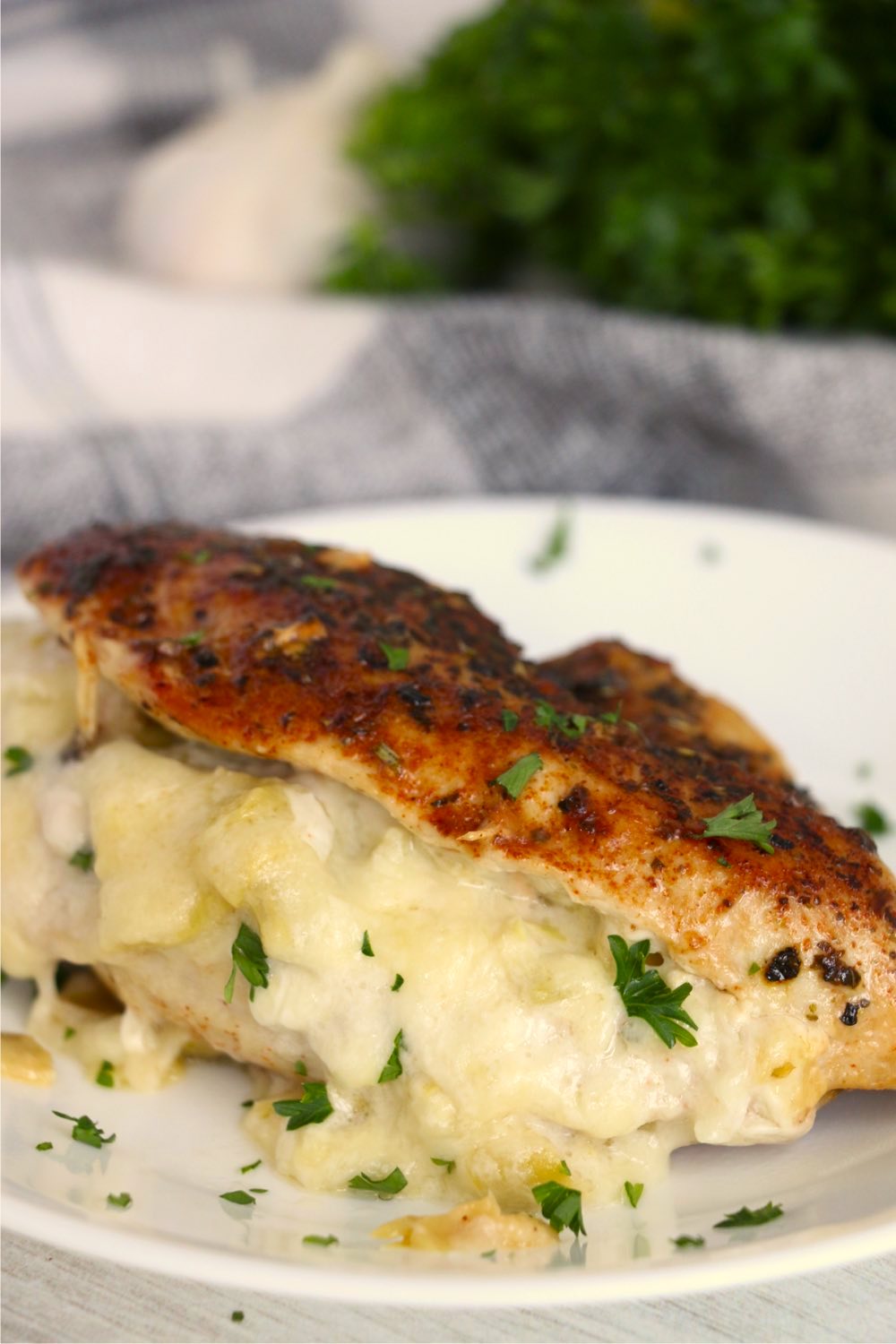 Artichoke stuffed chicken breast on a white plate