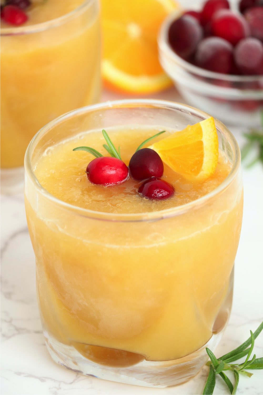 glass of brandy slush garnished with cranberries and an orange slice