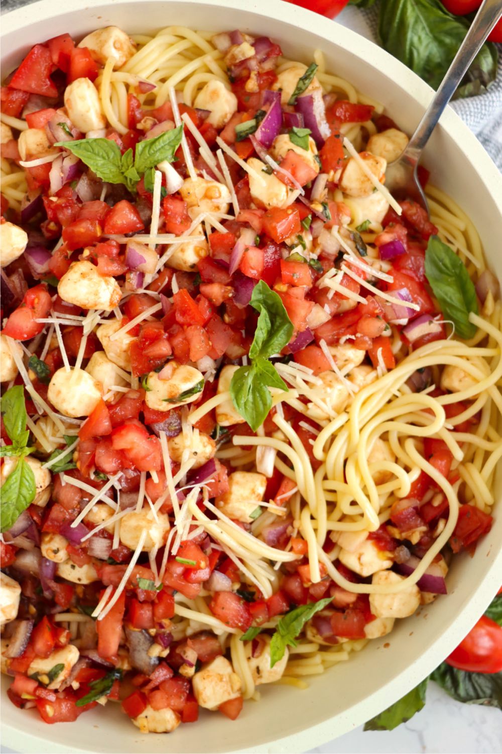 Big bowl of long spaghetti with tomatoes, mozzarella and basil.