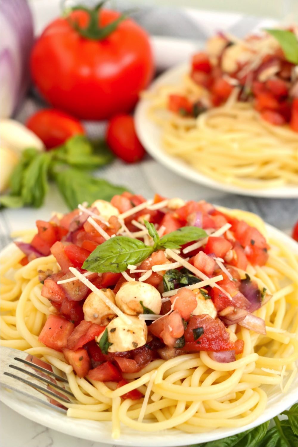 Bruschetta pasta salad on a white plate with a fork.