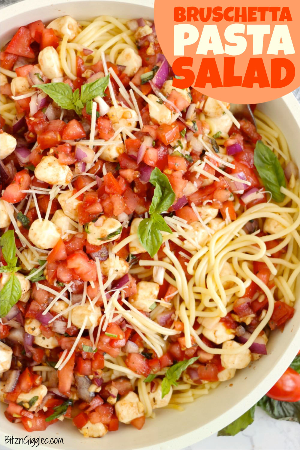 Huge bowl filled with long spaghetti, tomatoes, mozzarella, basil and parmesan cheese.