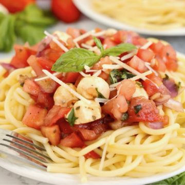 portion of spaghetti with a bruschetta topping on a white plate.