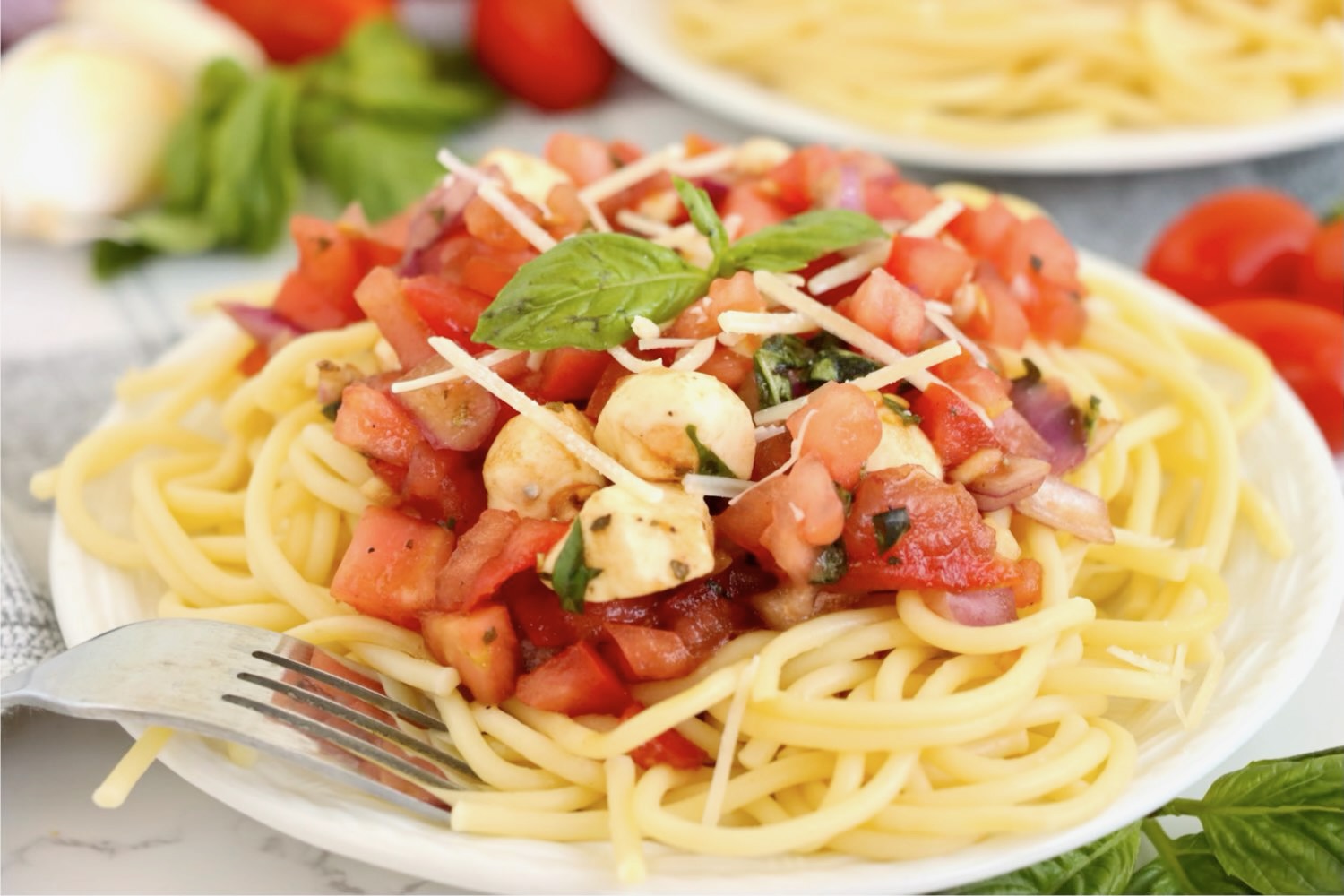 portion of spaghetti with a bruschetta topping on a white plate.