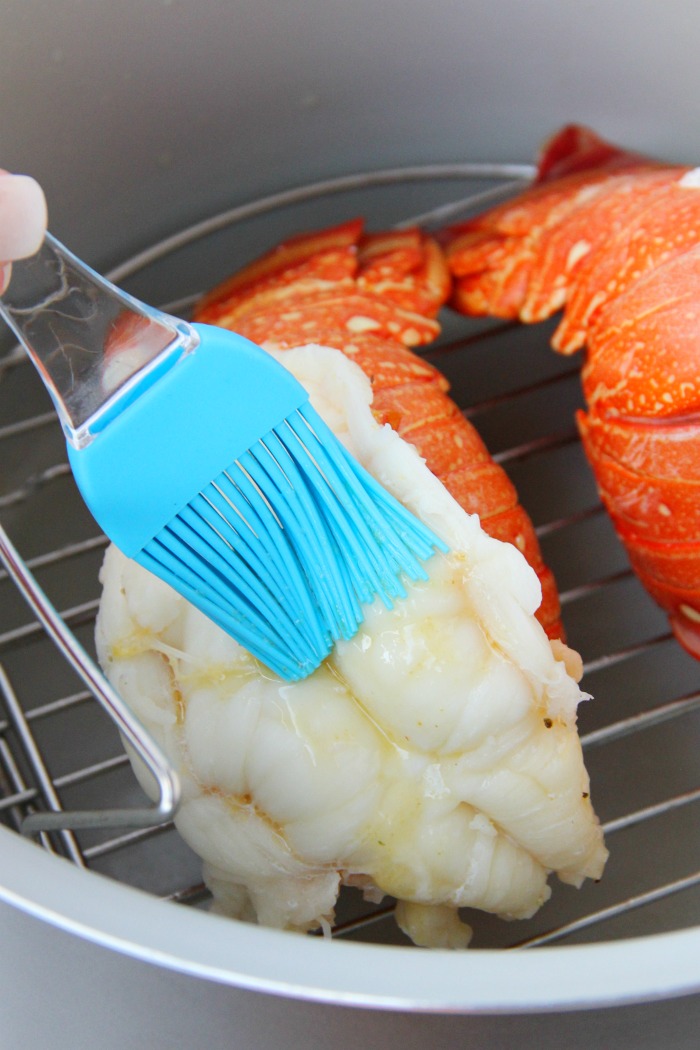 Brushing lobster tail with melted butter in Ninja Foodi