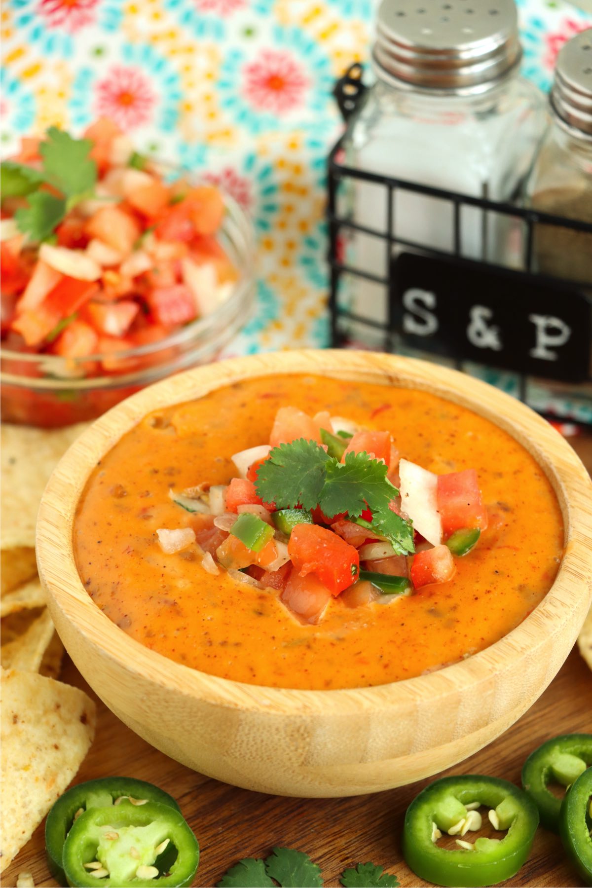small wooden bowl of chili con quest with diced onions, tomatoes and jalapeños
