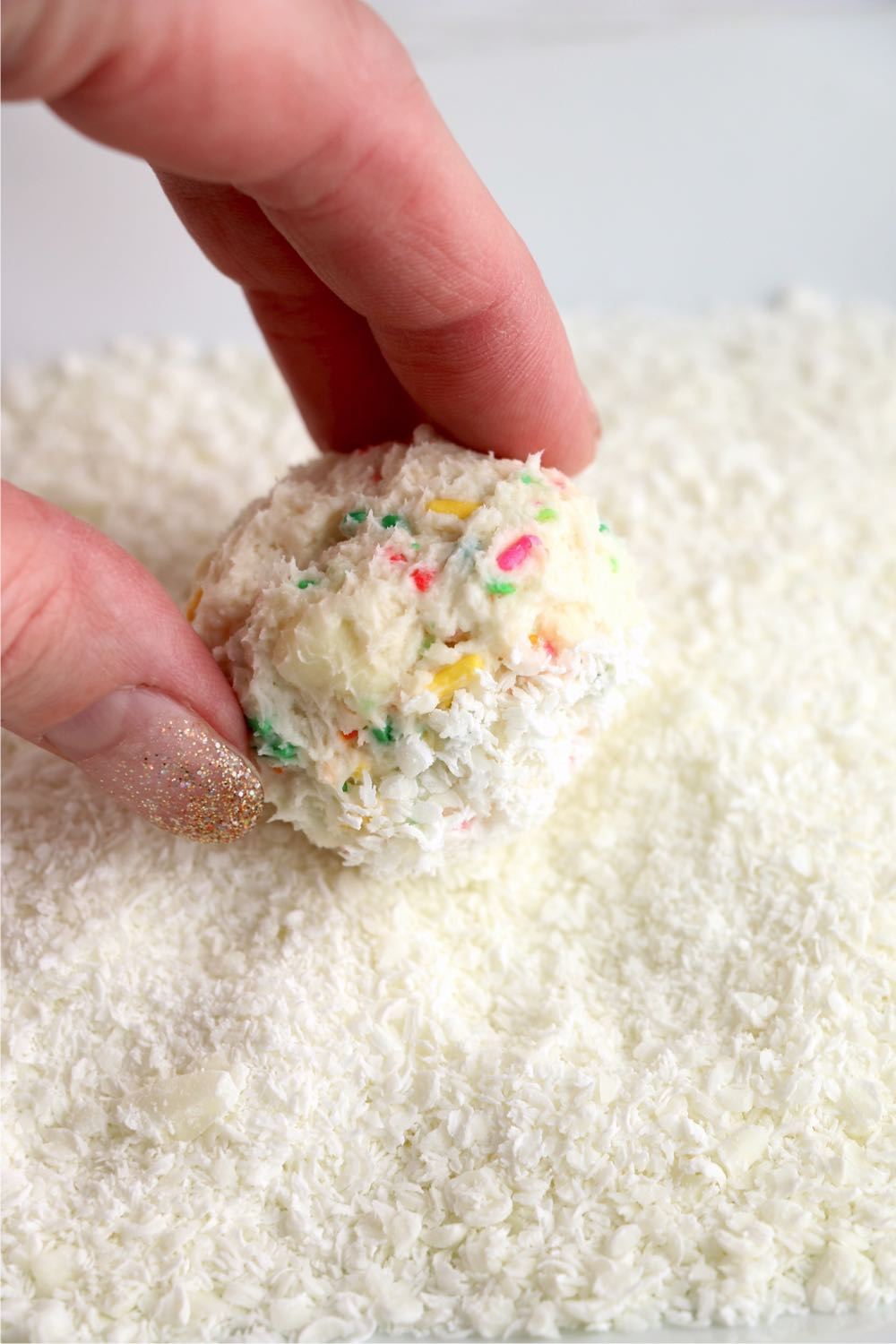 rolling cake ball in shaved white chocolate