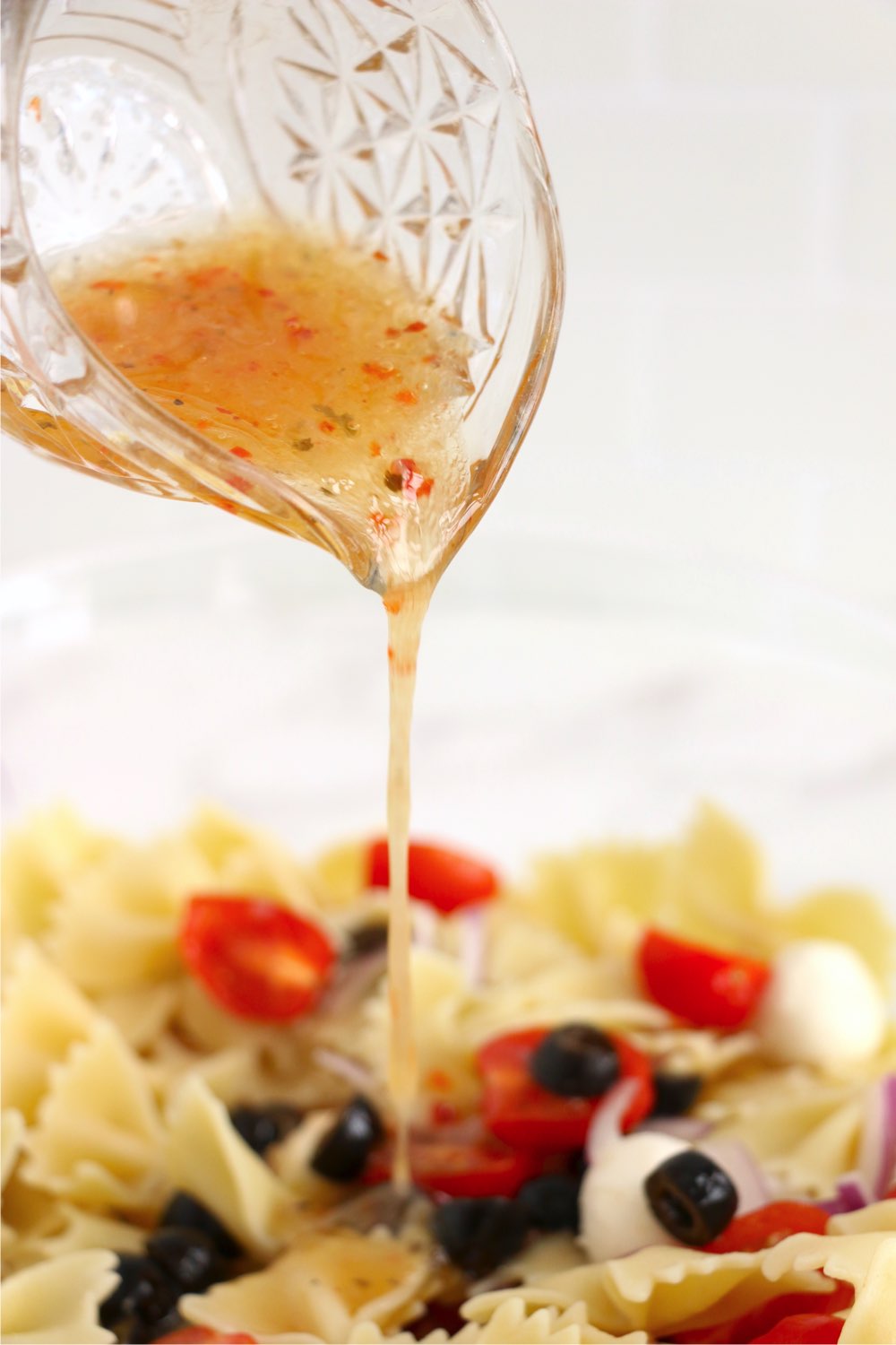 drizzling Italian dressing on pasta salad