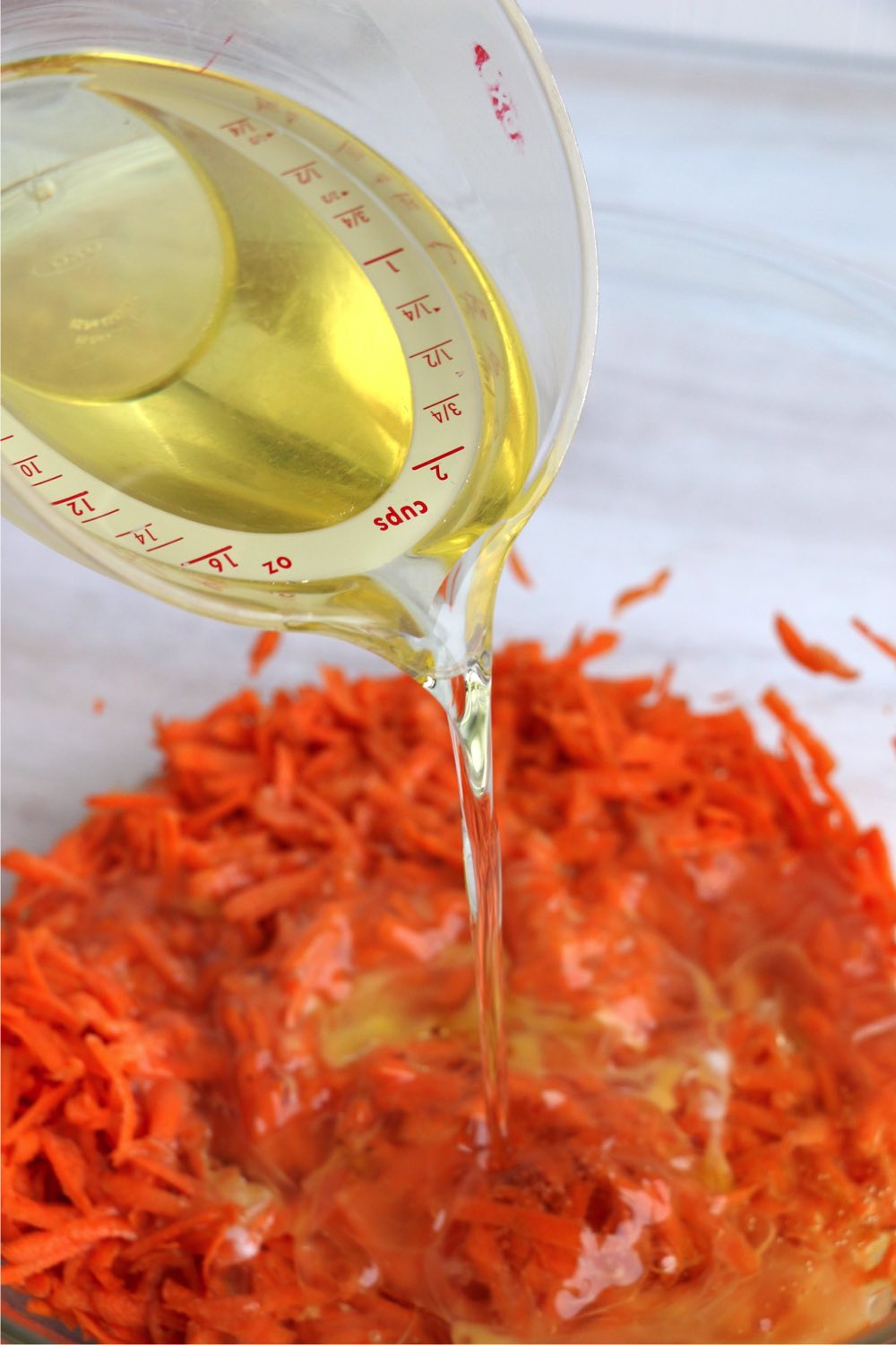 Adding oil to grated carrots in bowl