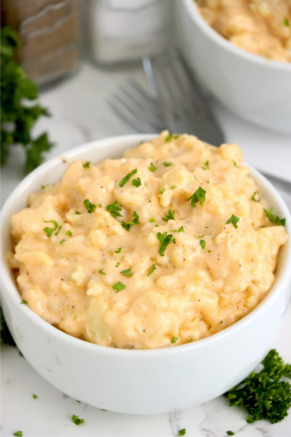 bowl of cheesy cauliflower garnished with parsley
