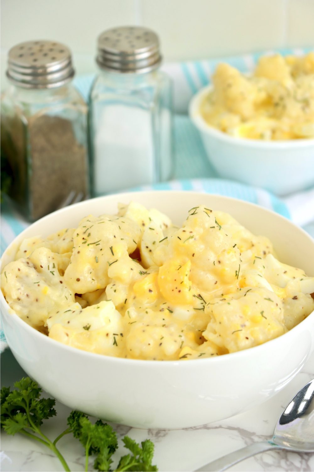 bowl of cauliflower salad with salt and pepper shakers in background