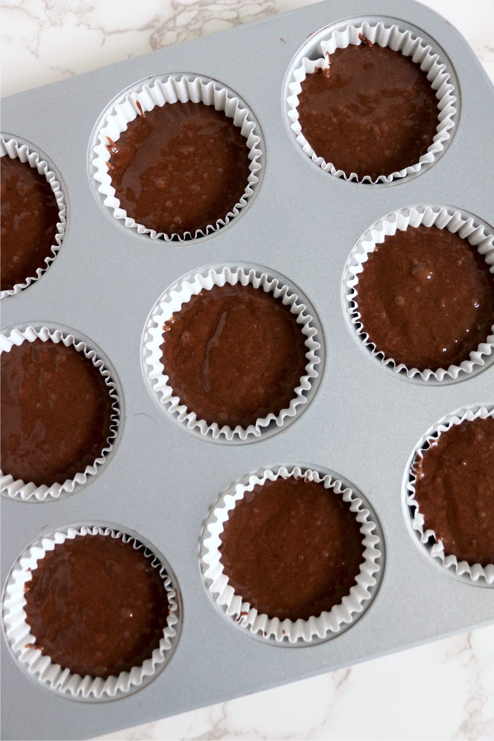 muffin tin cavities filled with cupcake batter