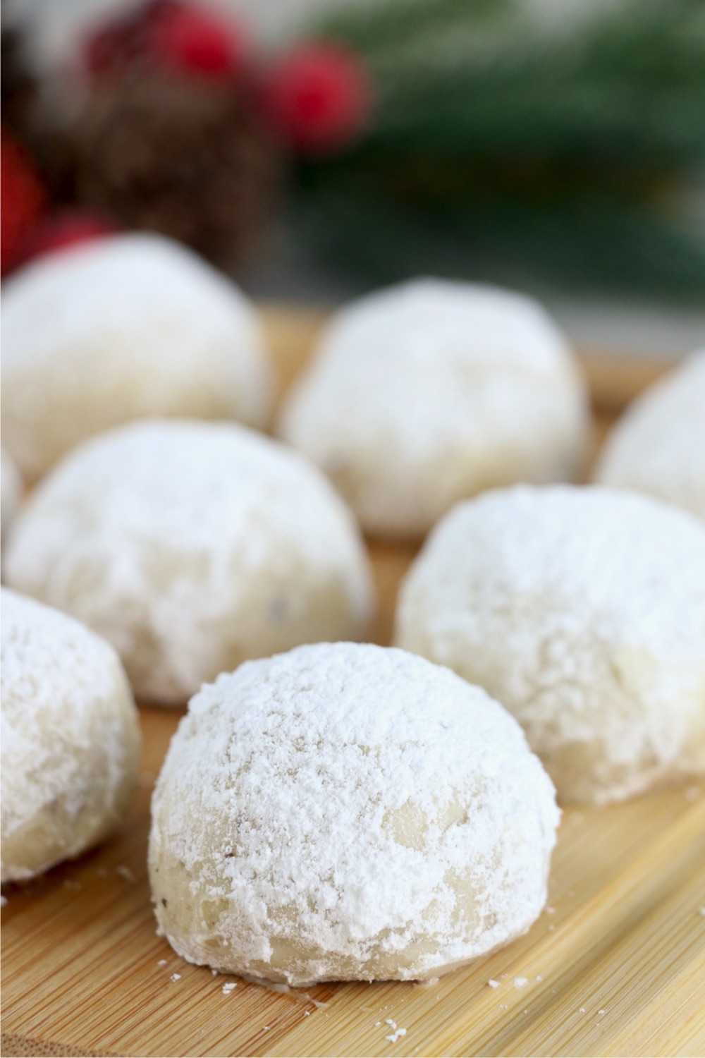 wooden cutting board filled with snowball cookies