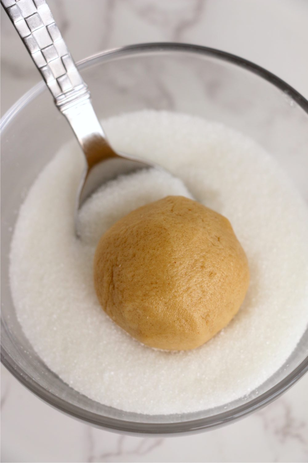 using a fork to dip cookie ball in sugar