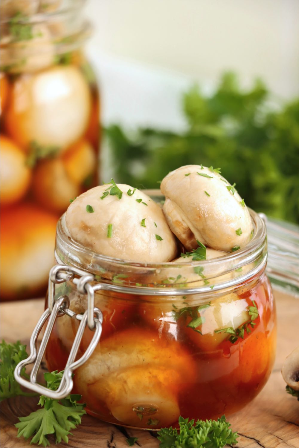 Open jar of marinated mushrooms sitting on a wooden table.