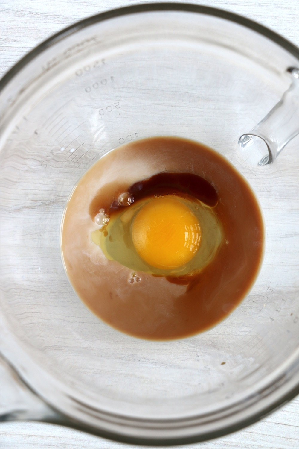 Egg, milk and vanilla in a glass bowl