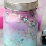 DIY Galaxy Jar -A gorgeous craft for kids, teens or even adults who love color and glitter! Simply layer cotton balls, acrylic paint, water and glitter shapes to create your own galaxy in a jar!