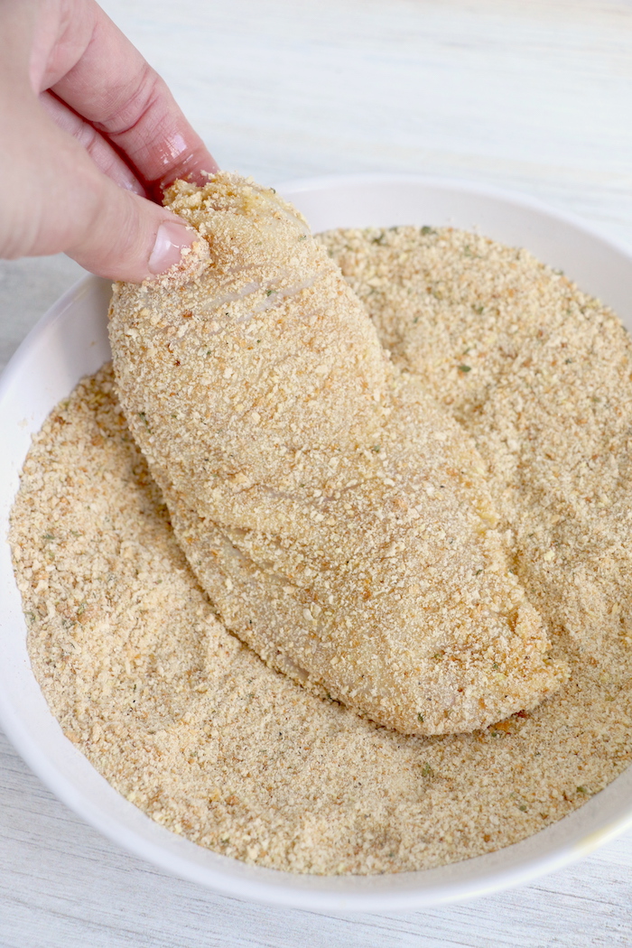 Dredging chicken breast in breadcrumb mixture