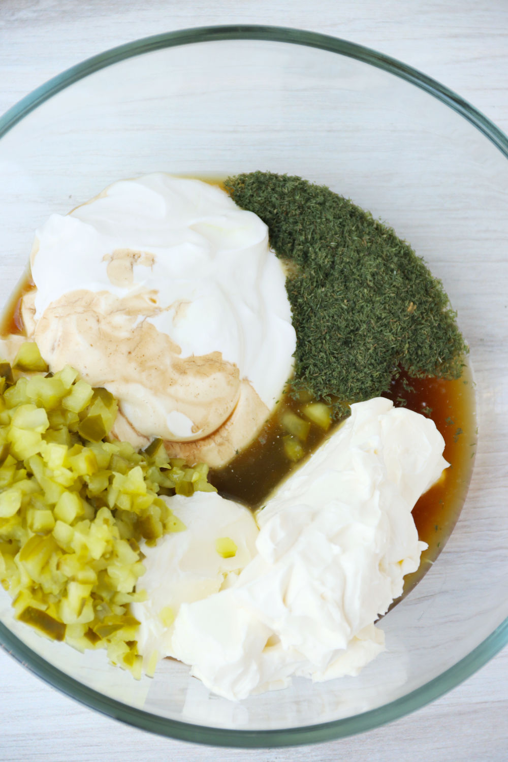 Ingredients for dill pickle dip in glass bowl