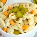 bowl of pasta salad with sliced pickles on top