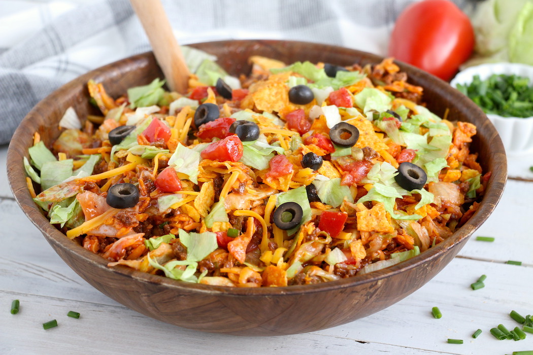 Dorito Taco Salad - This crunchy and zesty salad is made with seasoned ground beef, veggies, cheese and Doritos, then tossed with Catalina dressing. So delicious and serves a crowd!