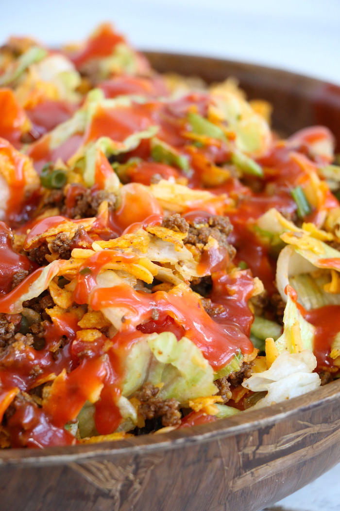 Dorito Taco Salad - This crunchy and zesty salad is made with seasoned ground beef, veggies, cheese and Doritos, then tossed with Catalina dressing. So delicious and serves a crowd!