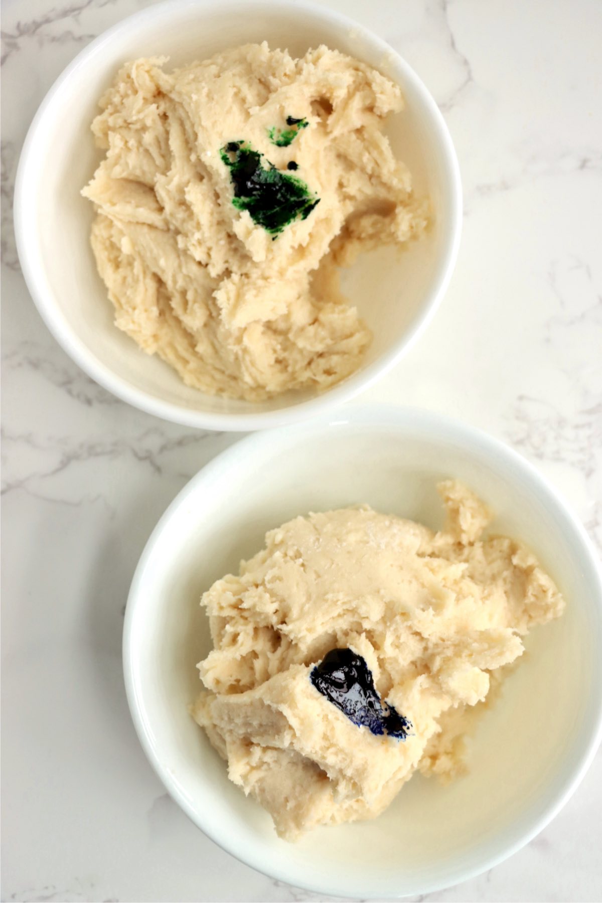 two bowls of cookie dough with food coloring on top