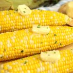 butter pats on cooked cobs of corn