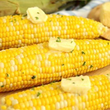 butter pats on cooked cobs of corn