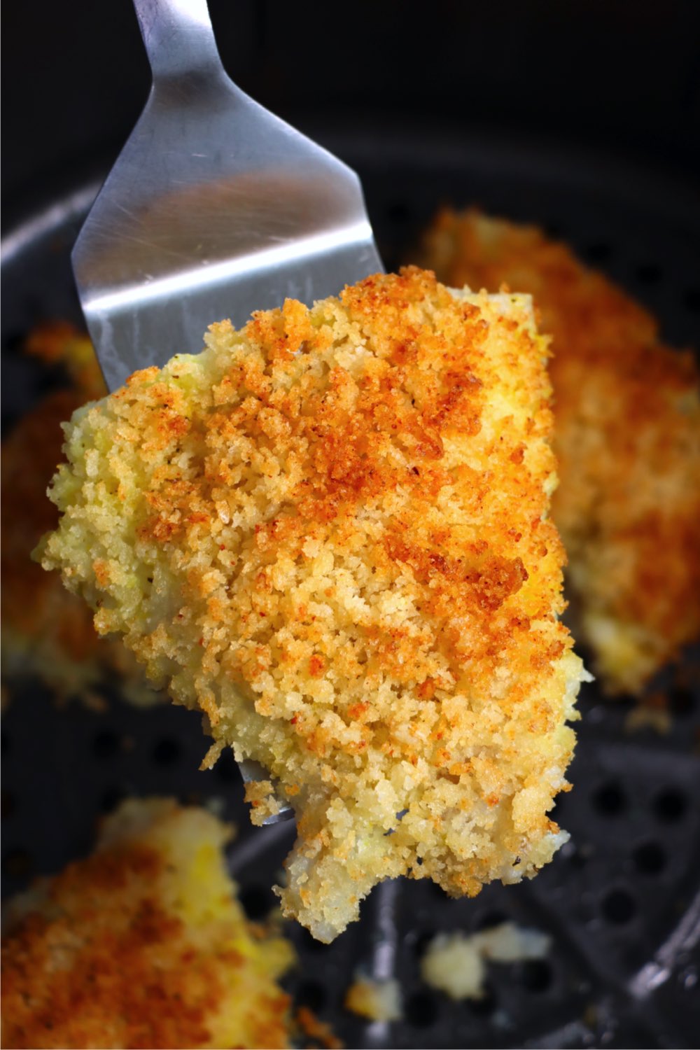 Spatula holding a piece of panic-crusted cod
