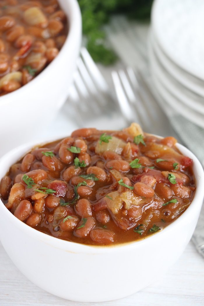 baked beans with fresh parsley in white bowl