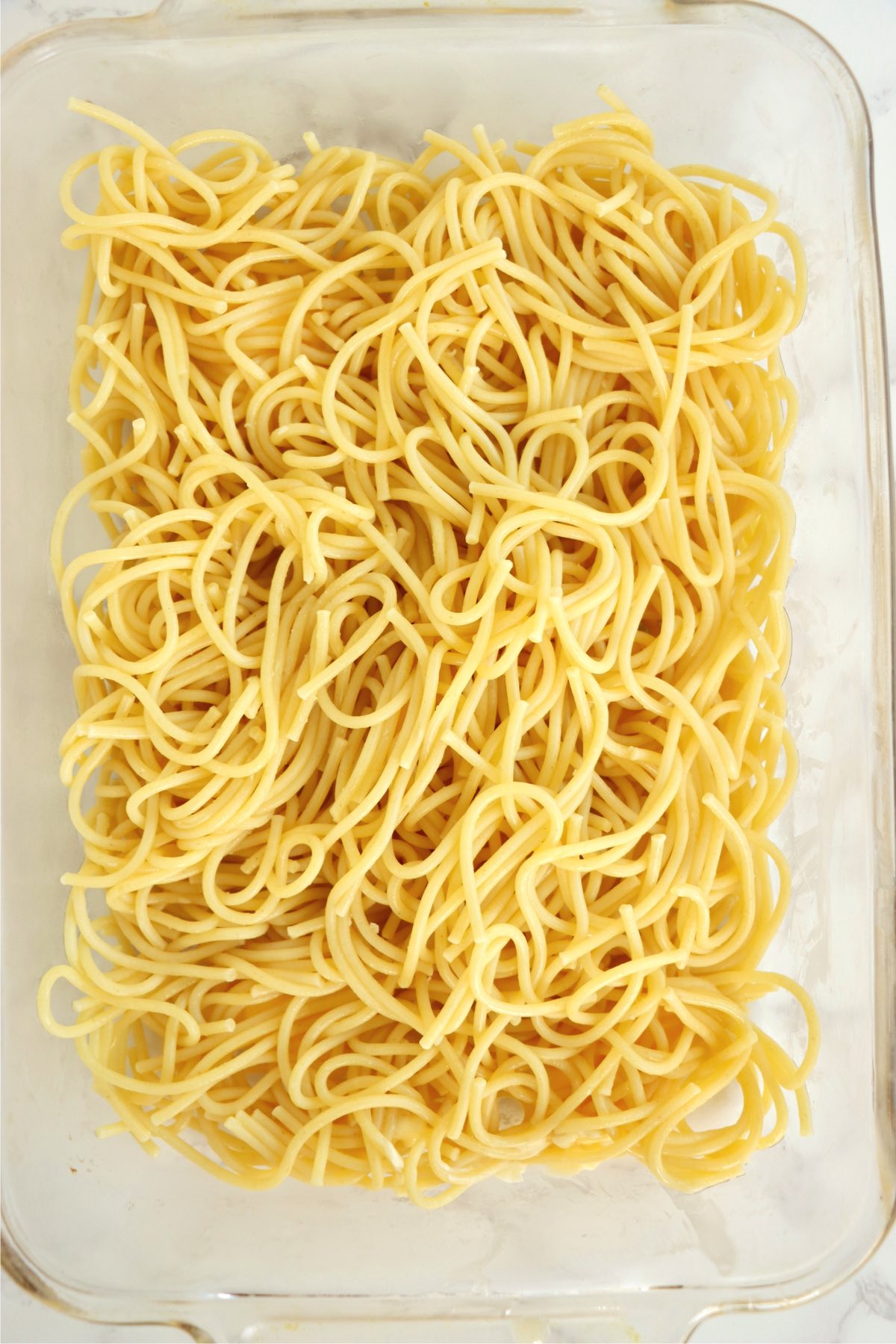 Glass baking pan filled with spaghetti noodles.
