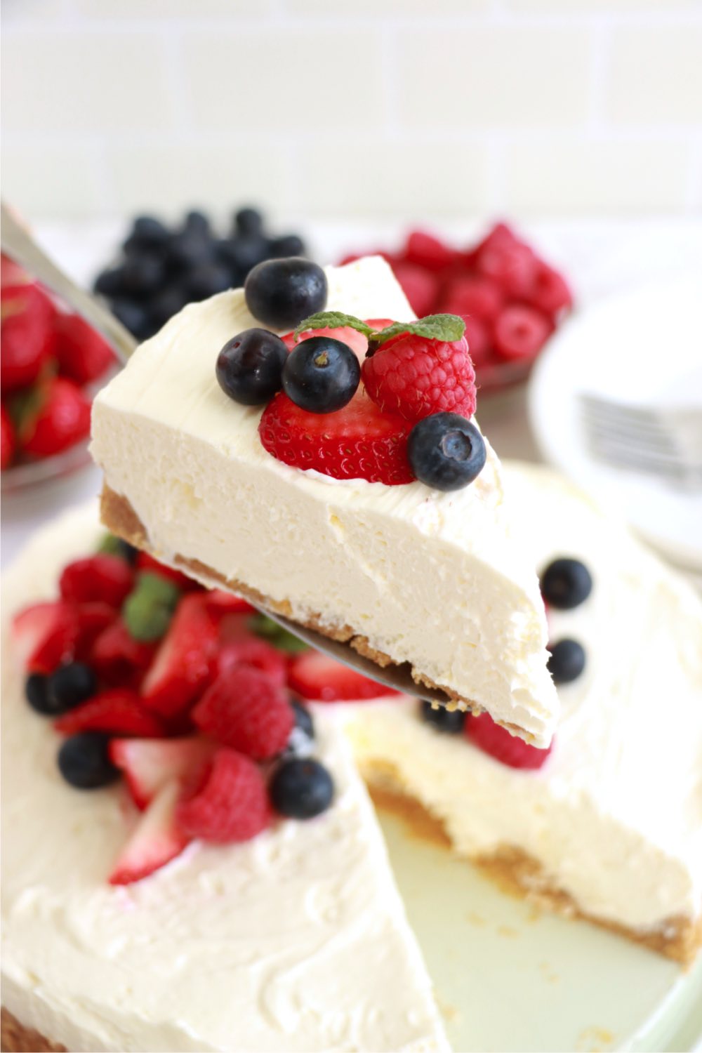 cake server holding a piece of berry-topped cheesecake