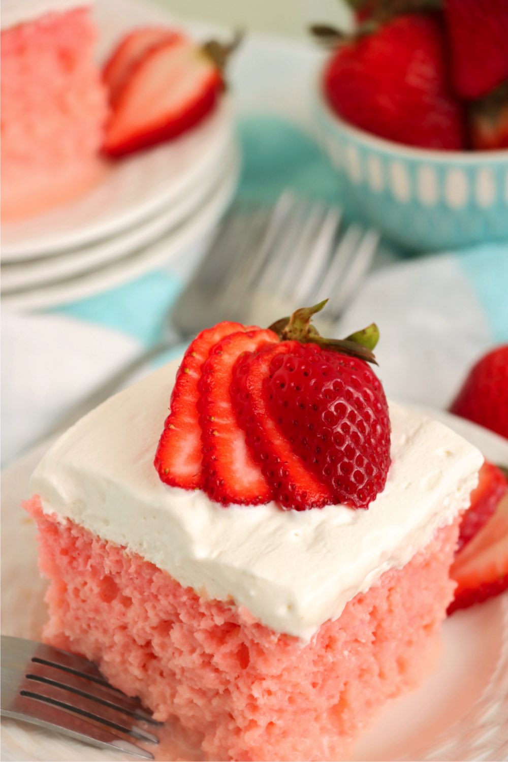 Strawberry tres leches cake garnished with strawberries on dessert plate