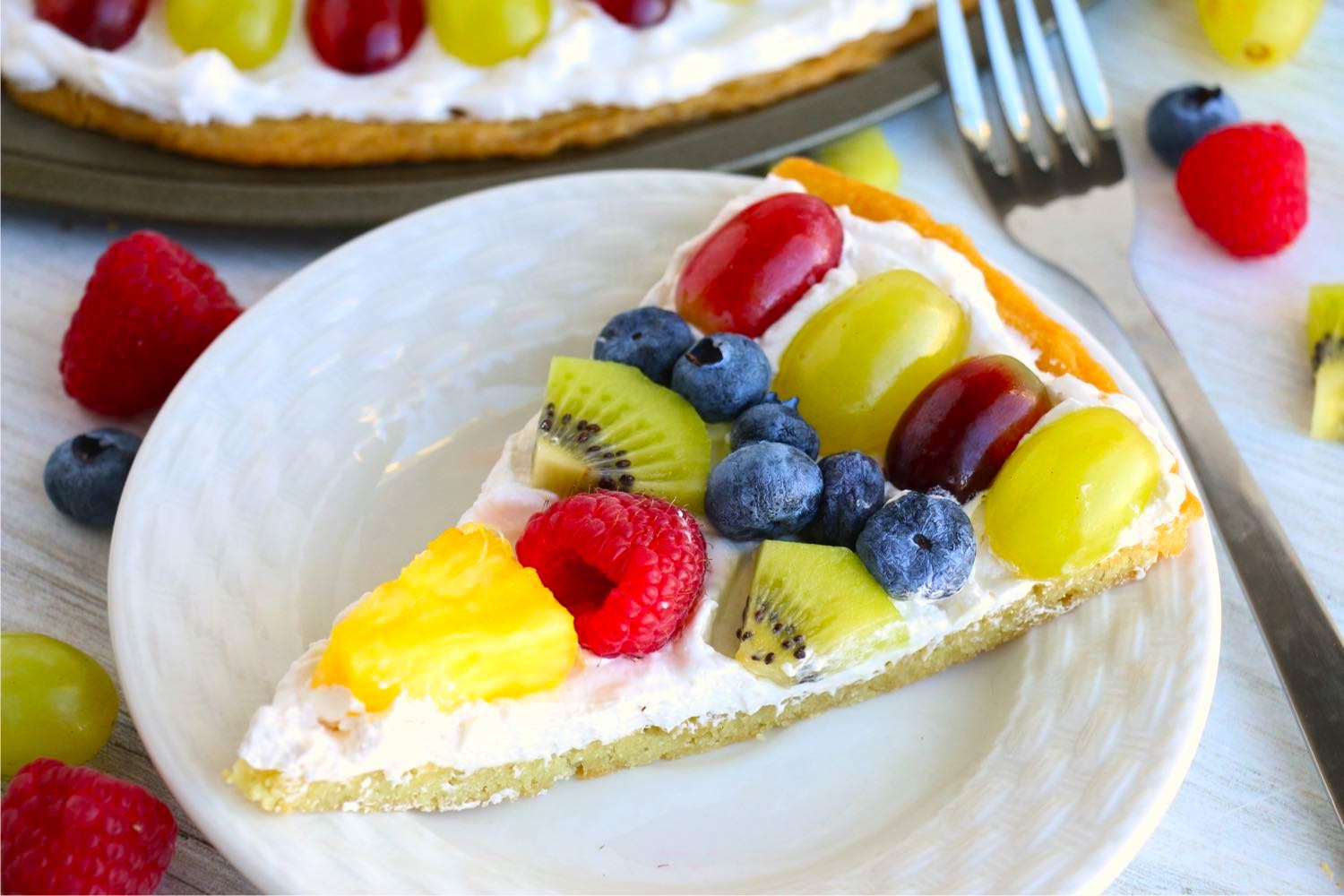 Slice of fruit pizza on a white dessert plate