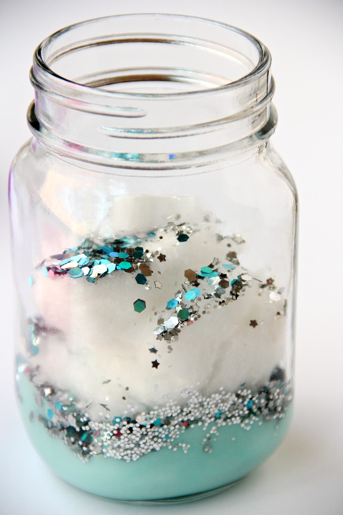 DIY Galaxy Jar -A gorgeous craft for kids, teens or even adults who love color and glitter! Simply layer cotton balls, acrylic paint, water and glitter shapes to create your own galaxy in a jar!