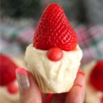 hand holding up a gnome cupcake with a strawberry hat