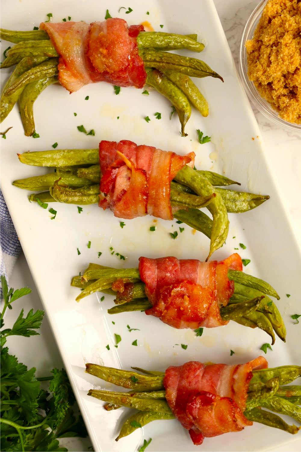 Green bean bundles arranged on a white serving plate