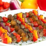 white platter filled with colorful meat and veggie kabobs