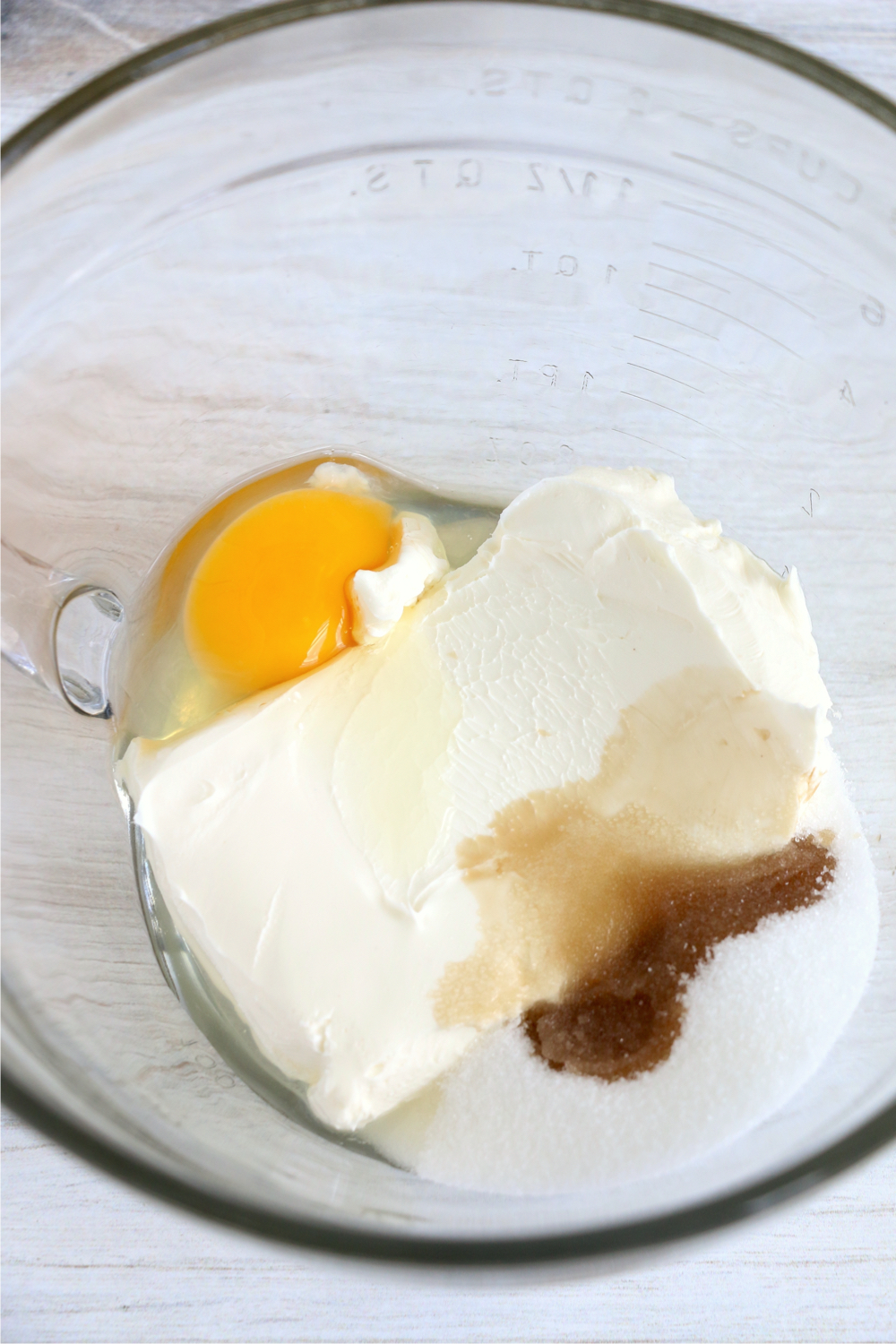 cream cheese, sugar, vanilla and an egg in a glass bowl