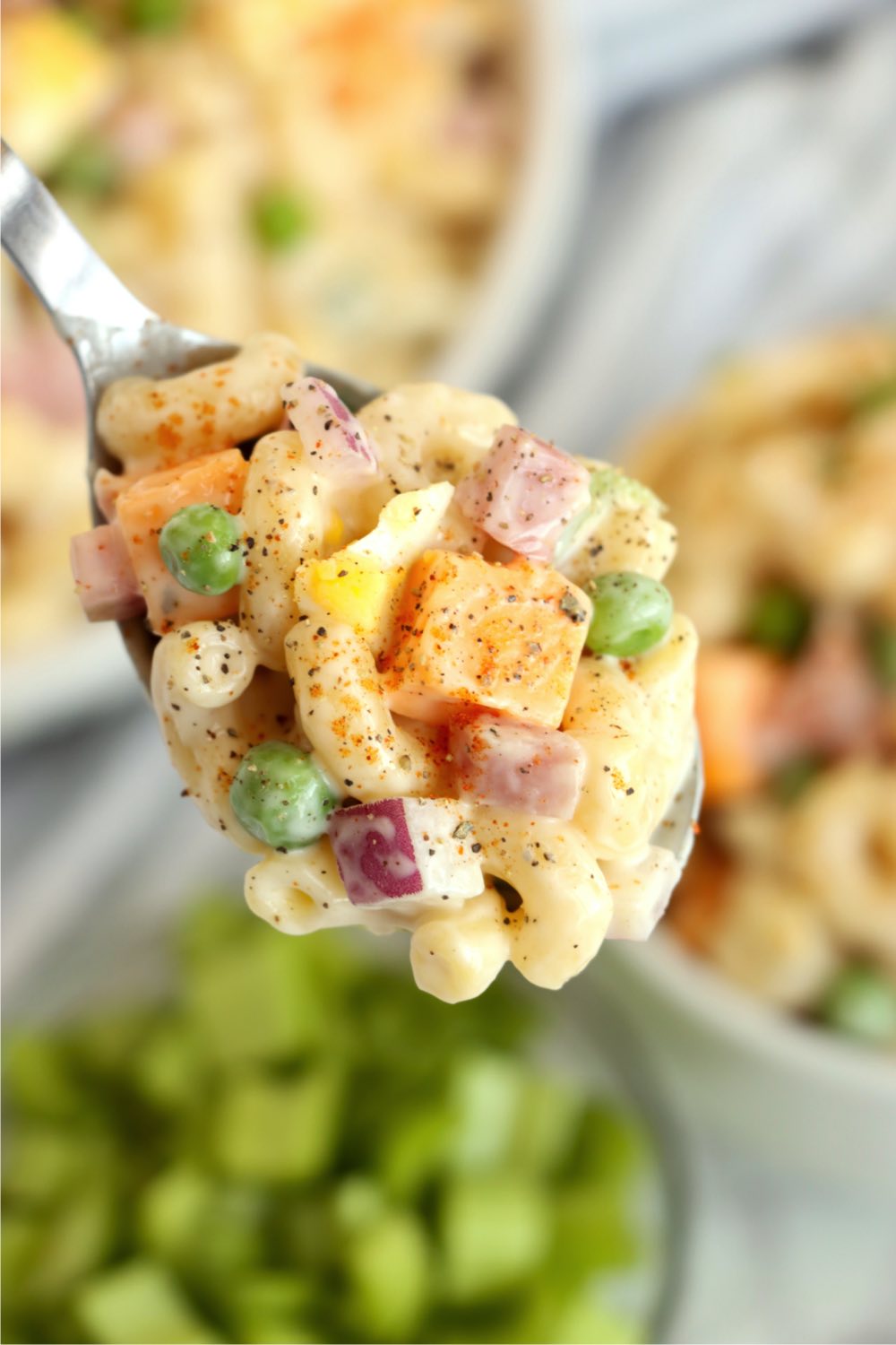 A serving spoon filled with pasta salad with cheese