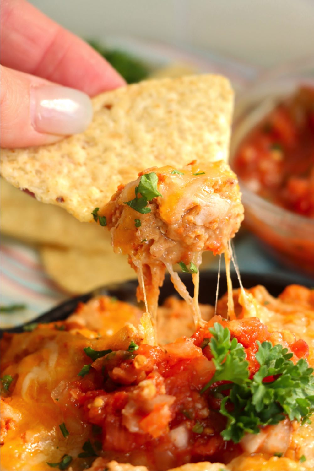 chip with cheese pull dipping into bean dip