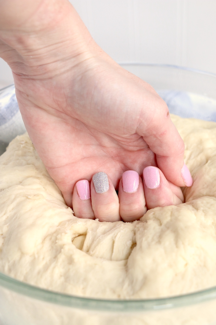 A hand punching bread dough down