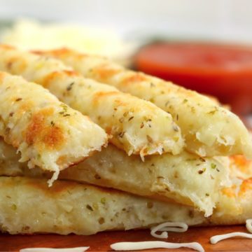 cheesy breadsticks in front of bowls of dipping sauce